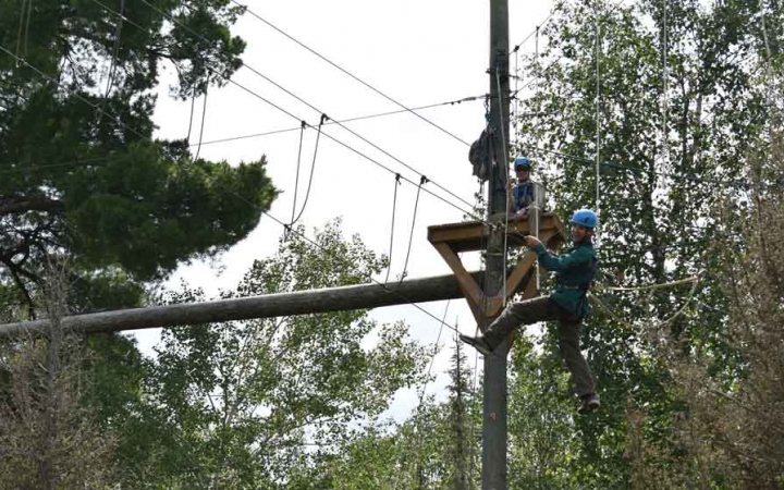 a student balances on ropes while participating in a high ropes course with outward bound